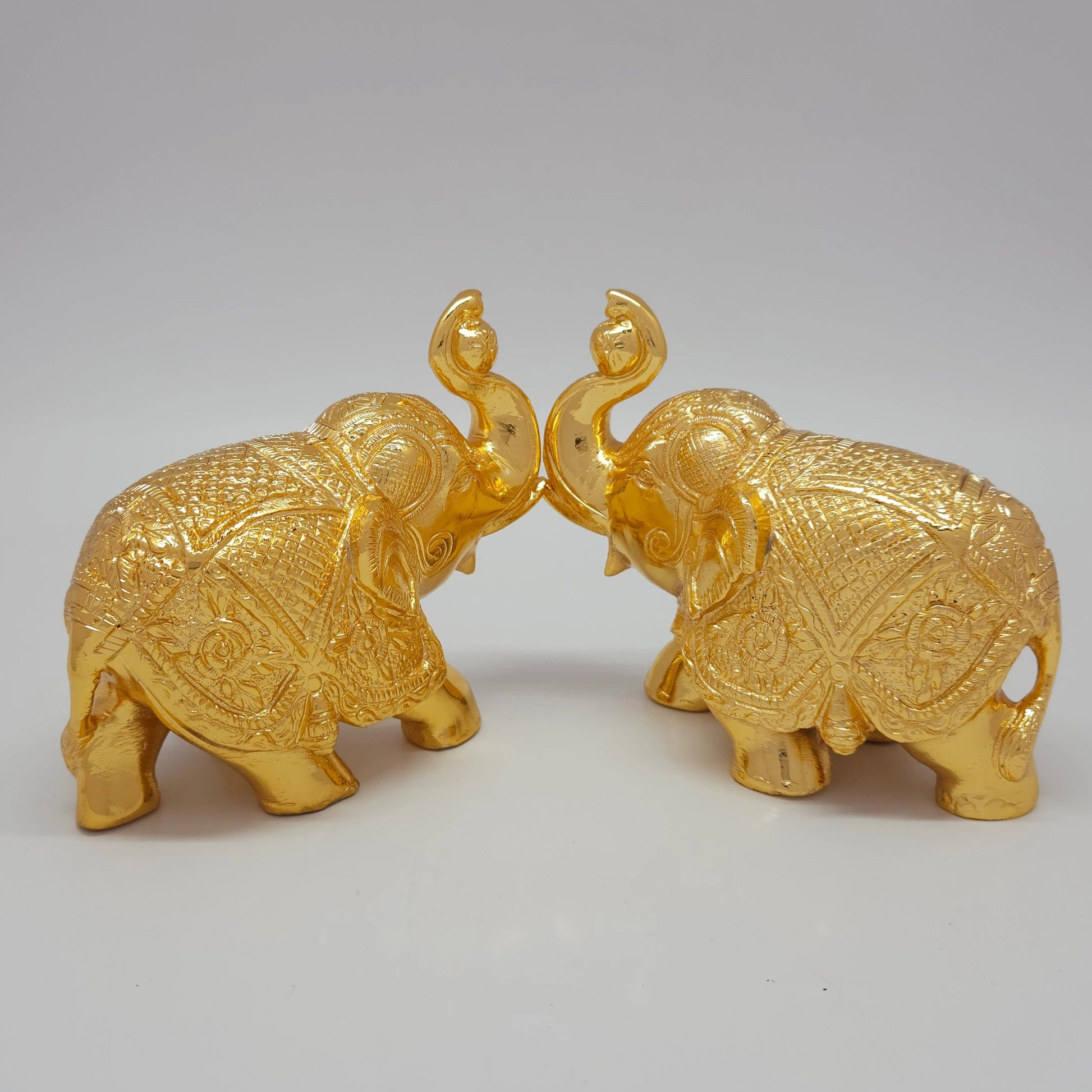 Sri Swaminathan and Co brass elephant statue gold powder coated 4-inch 11cm height posture mirror view facing each other 45-degree side showing uniform satin gold finish layer