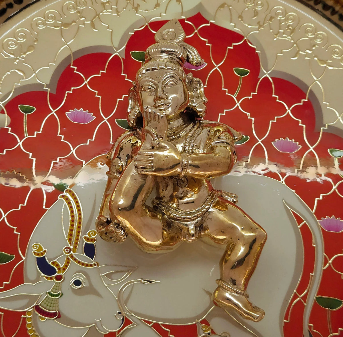 Premium lifestyle display of the Swamimalai Panchaloha Baby Krishna Murti paired with a red traditional temple arch background for luxury living room decor.