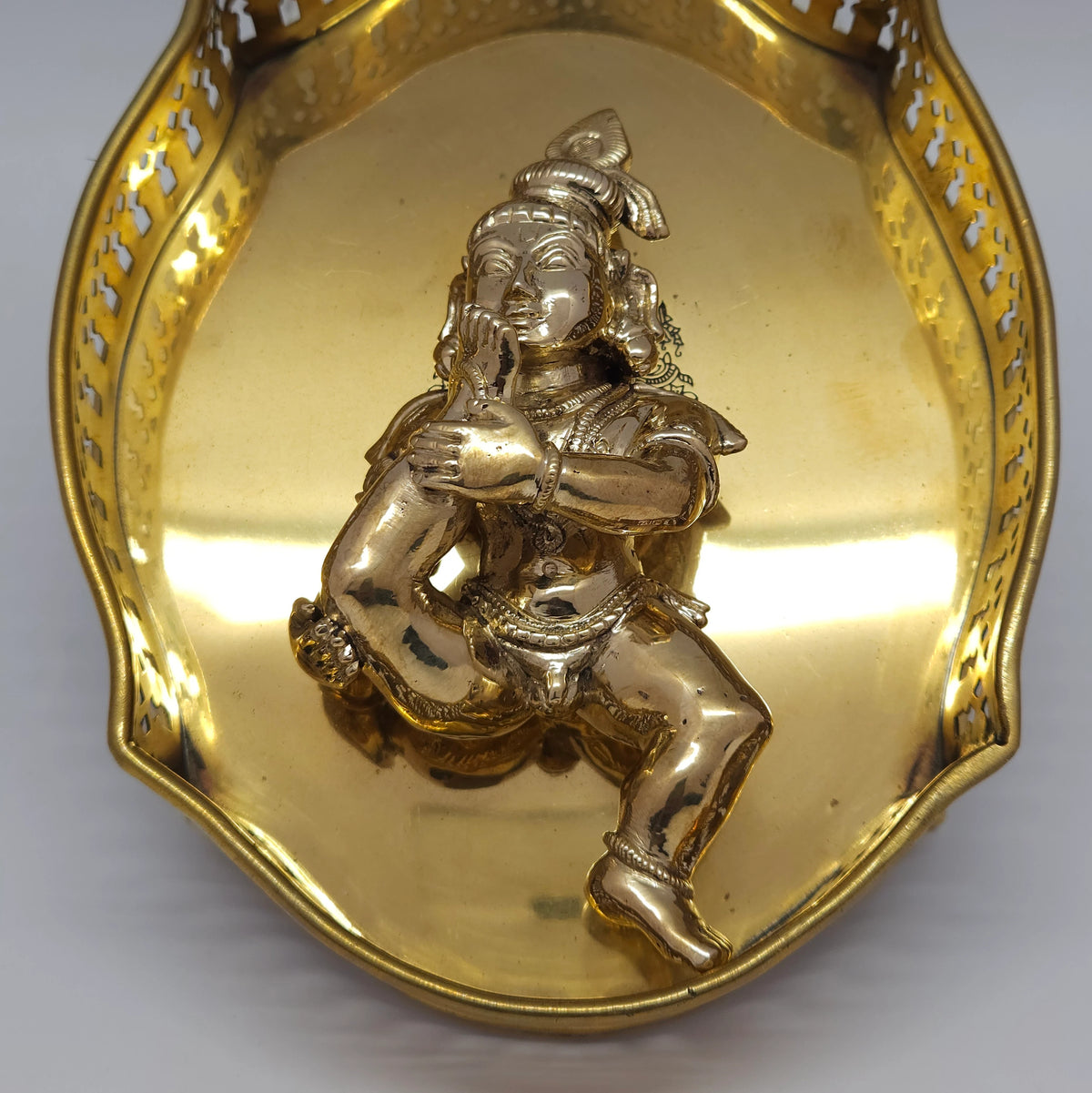 Top-down view of the authentic Swamimalai Panchaloha Baby Krishna tasting toe idol placed inside a polished brass pooja thali for home altar inspiration