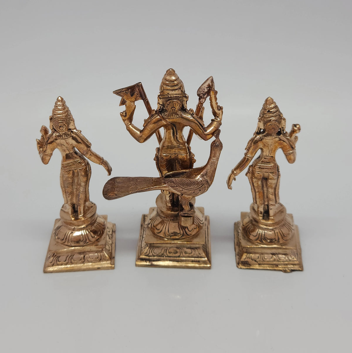 High angle back view of the handmade five-metal Lord Murugan idol trio highlighting the fine facial features and metal casting details.
