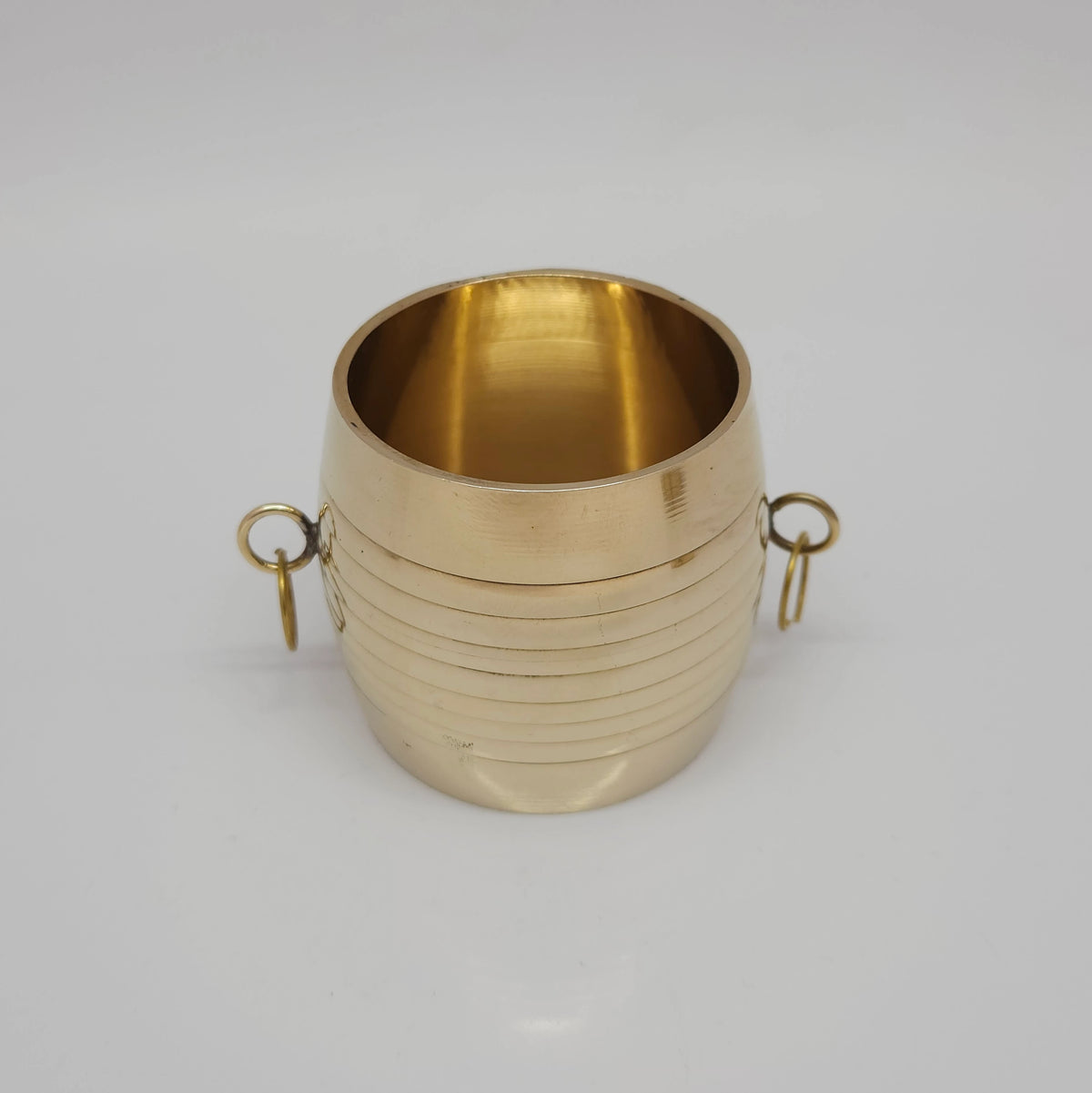 Three-quarter tilted perspective view of a single traditional brass changazhi grain measure cup focusing on the smooth open rim compartment.
