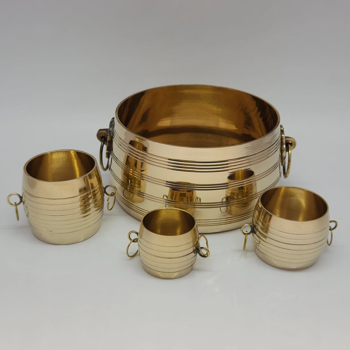 Four-piece nested set of premium pure brass chiri padi measuring vessels with distinctive side drop rings and concentric machine-grooved lines.
