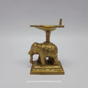 Full side profile view of pure brass gaja vilakku oil lamp showcasing the detailed trunk carving and raised pillar design.
