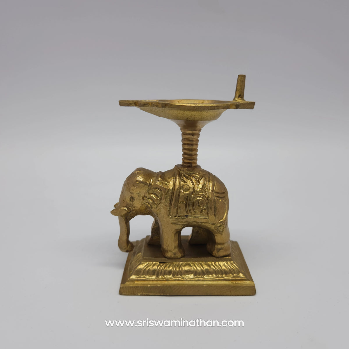 Full side profile view of pure brass gaja vilakku oil lamp showcasing the detailed trunk carving and raised pillar design.