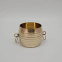 Standalone front profile shot of a traditional pure brass padi measuring vessel showing detailed concentric grooves and side drop rings.

