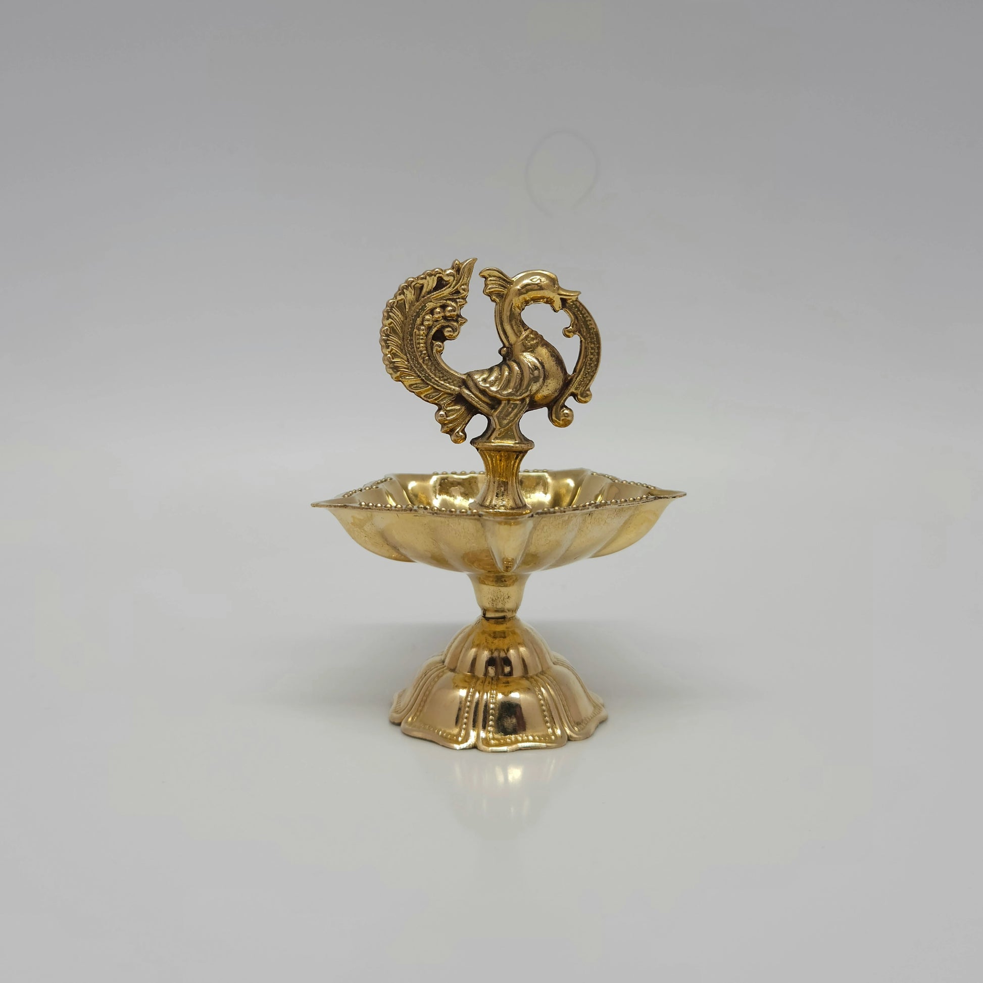 Front look of the 5-wick pure brass peacock vilakku on a clear white background.