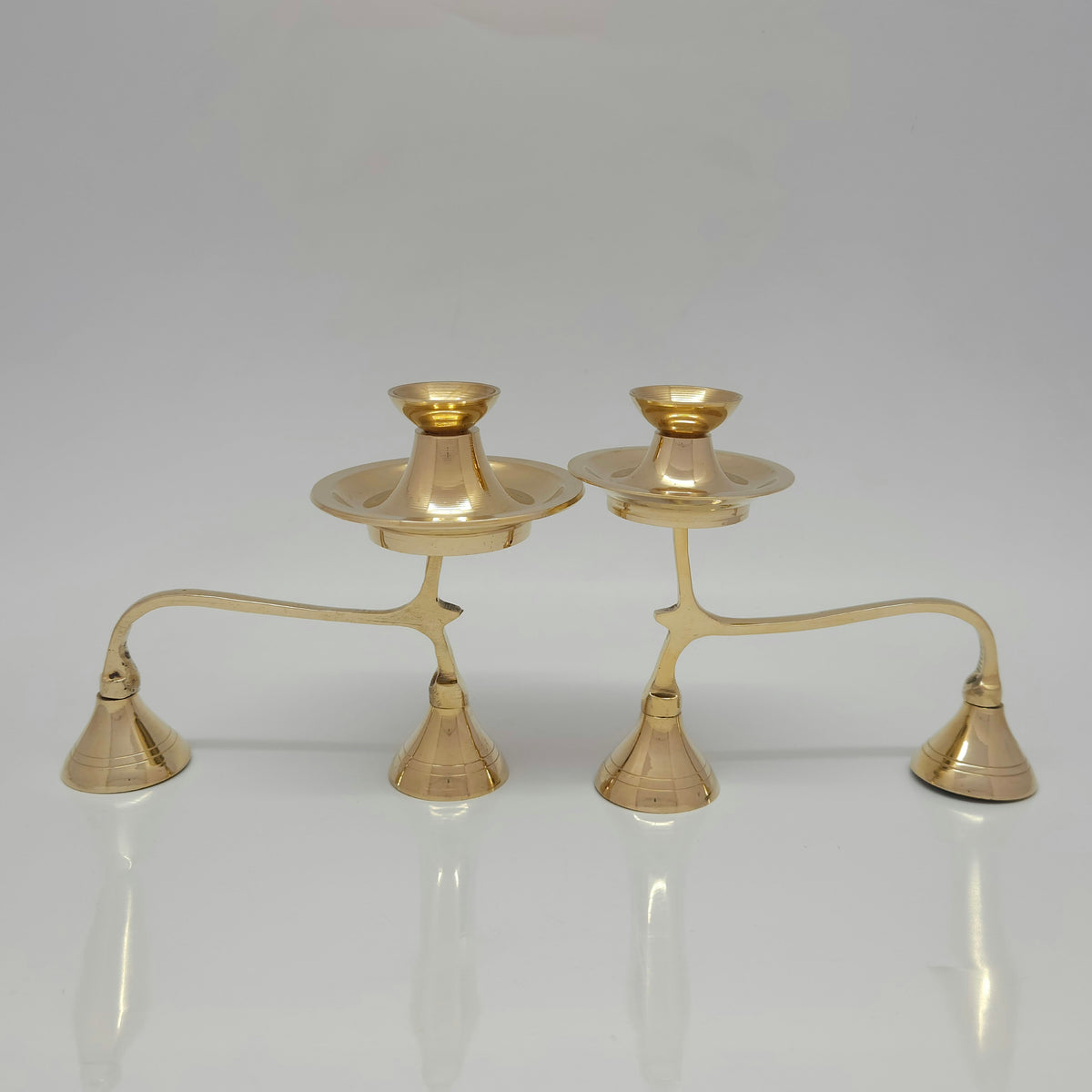 Two genuine brass camphor aarti stands with handles placed side by side to highlight the design details of the extra storage disk.